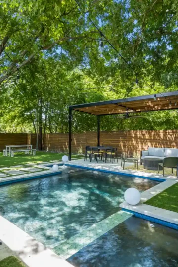 Swimming pool in the backyard of a home in Pine Forest. The pool is surrounded by trees and a patio.