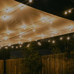 Backyard shown at night with string lights illuminating the space.