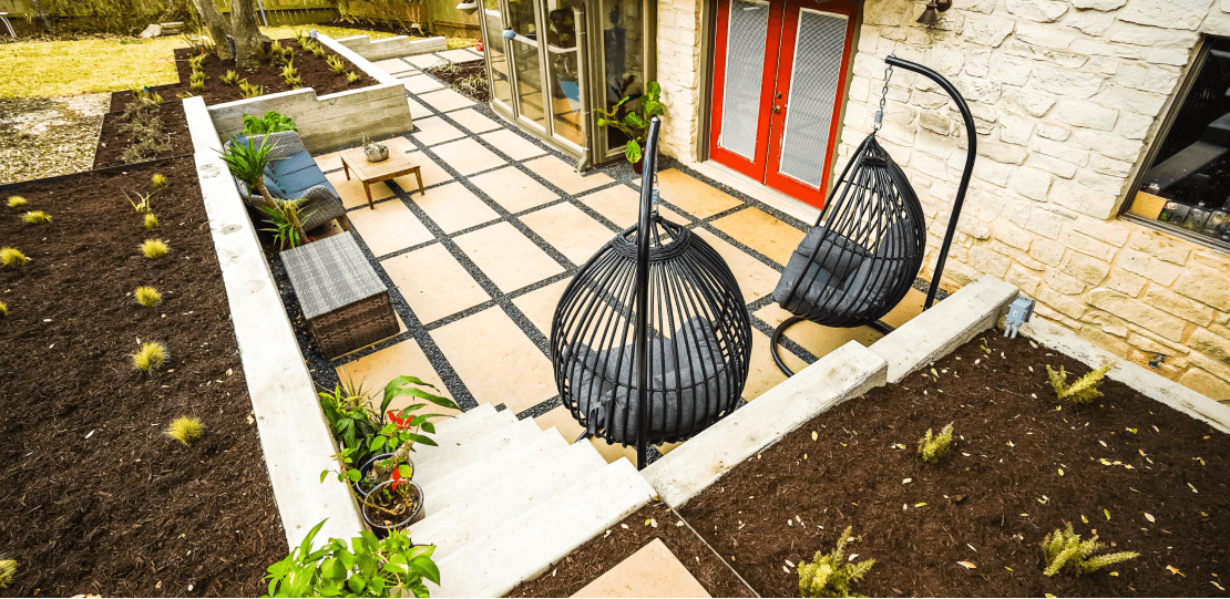 A paver hardscaping patio area with 2 hanging pod chairs.