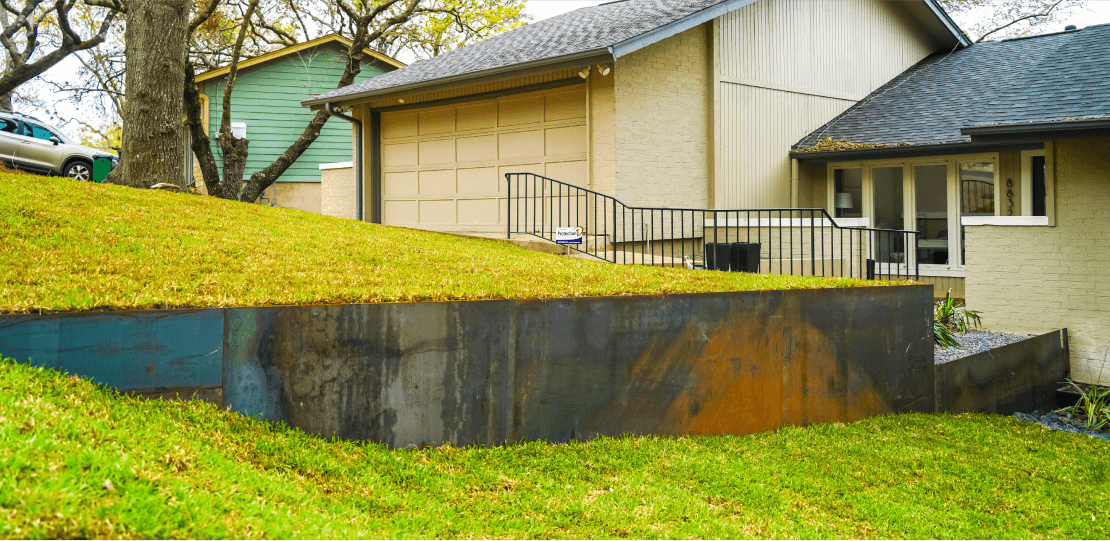 An unfinished dividing wall in a grassy backyard.