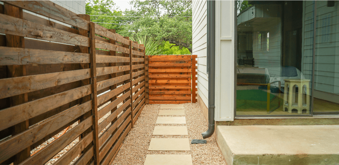 Cutters-Fences & Gates 7 A wooden fence with horizontal slats and paved stone path.