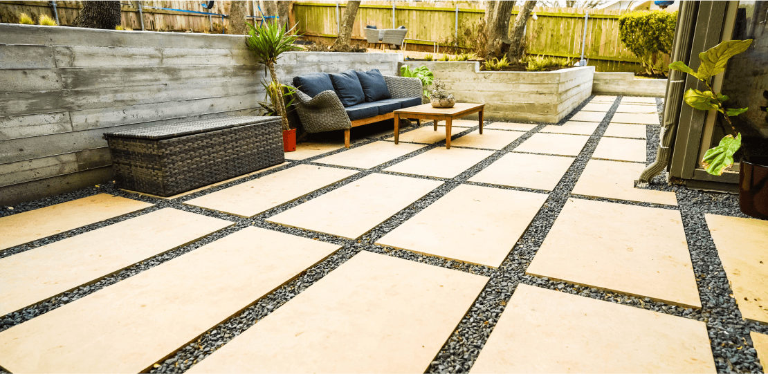 Smooth, rectangular pavers arranged in a grid surrounded by gravel.