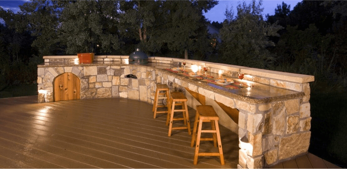 A long, curved stone bar with 3 wooden bar stools.