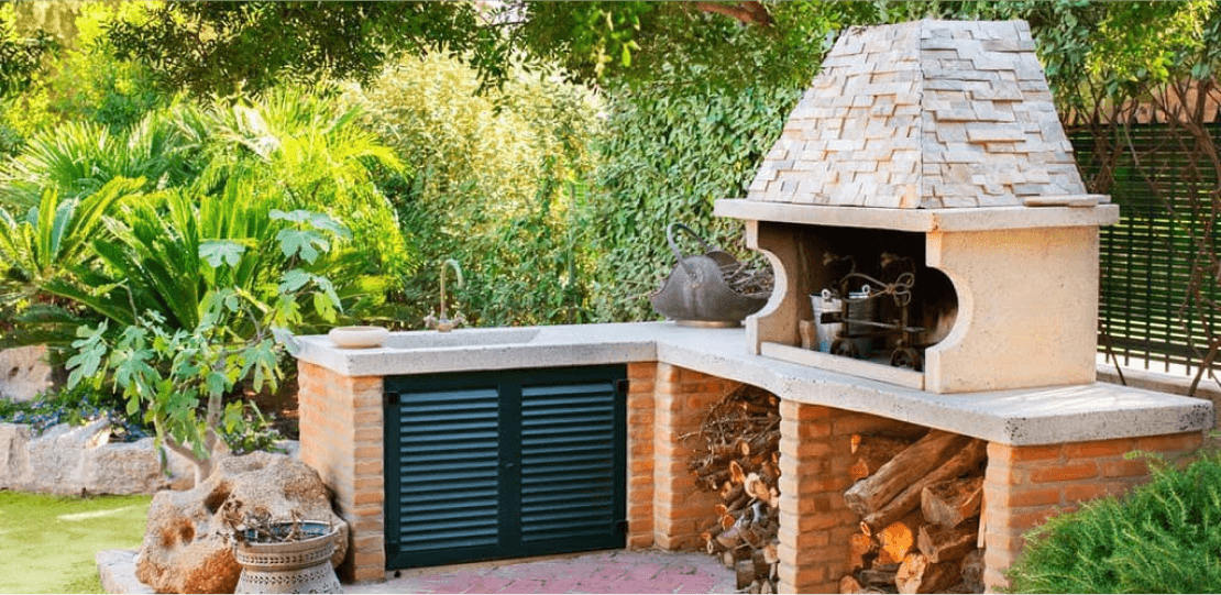 An outdoor wet bar and stone hutch with firewood storage.