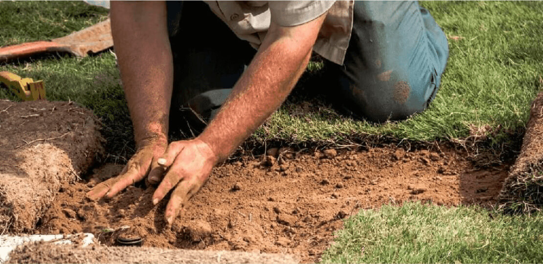 A person's hands compacting dirt.