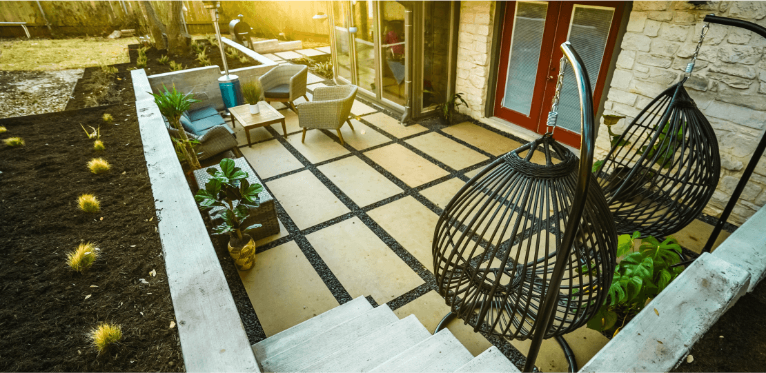 A paver hardscaping patio area with 2 hanging pod chairs.