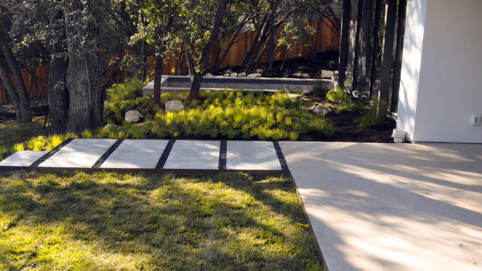White rectangular pavers laid in a path leading to a concrete patch.
