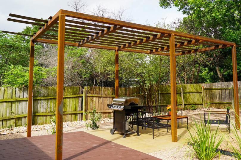 Metal pergola with a grill under it.