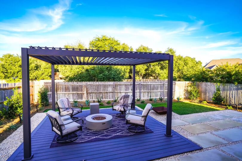Metal pergola with 4 chairs and a fire pit underneath it.