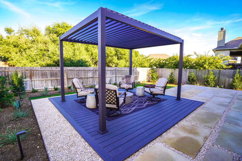 Metal pergola with 4 chairs and a fire pit underneath it.