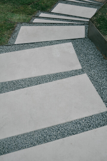 Close up of white rectangular stone steps surrounded by small grey pebbles.