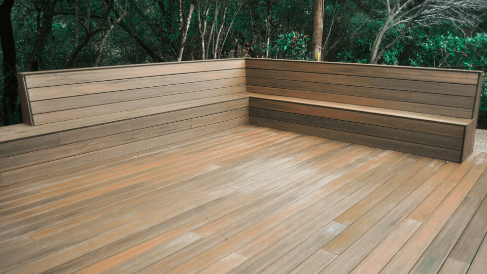 Wooden deck with a built in bench. Trees can be seen in the background.