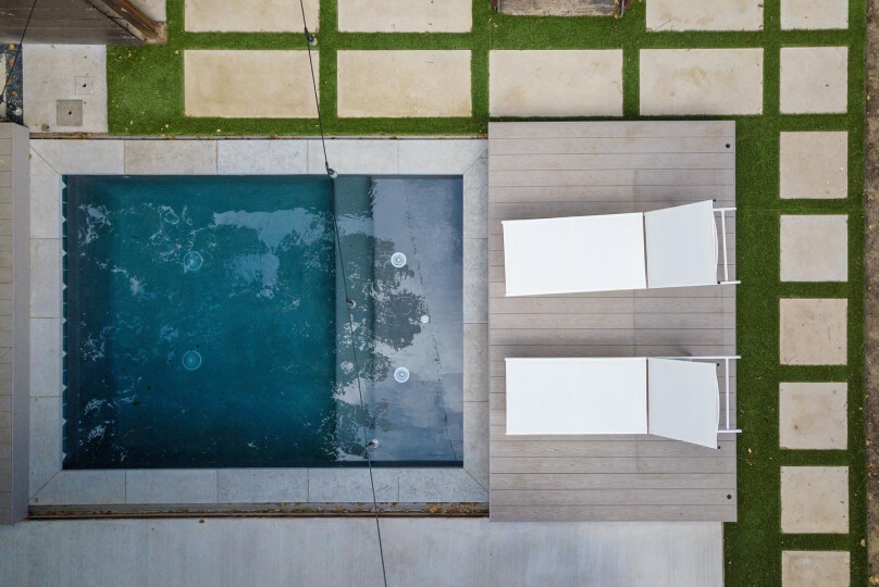 Birds eye view of a pool with two white pool chairs on the side of the pool