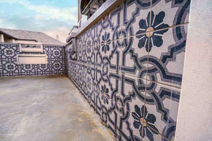 Side view of a outdoor kitchen with white and blue floral tile.