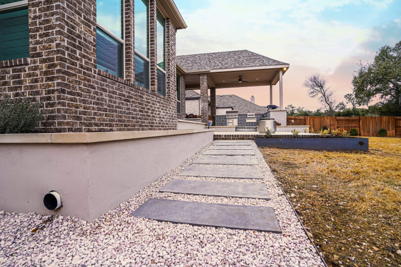 Photo of a back patio from a ground angle. You can see a stone pathway leading up to the patio.