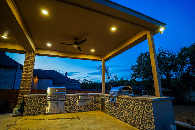 A photo of the patio cover at night. You can see four lights and a fan.