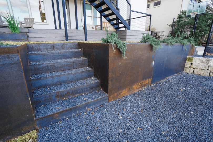Close up of metal stairs and planters in a landscaped backyard.