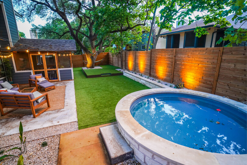 SIde view of a backyard with a pool, green grass, and landscaped stone steps