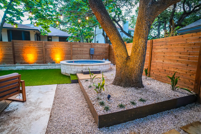 Landscaped backyard with a large tree and a small pool.
