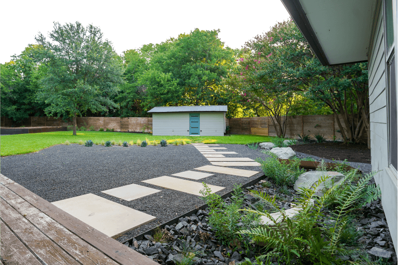 View of a landscaped backyard with a shed in the background.