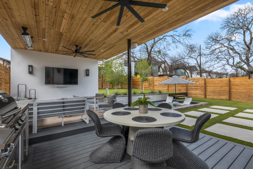 Landscape design in Rosedale, Austin with covered patio, outdoor kitchen, stone pavers, and a swimming pool.